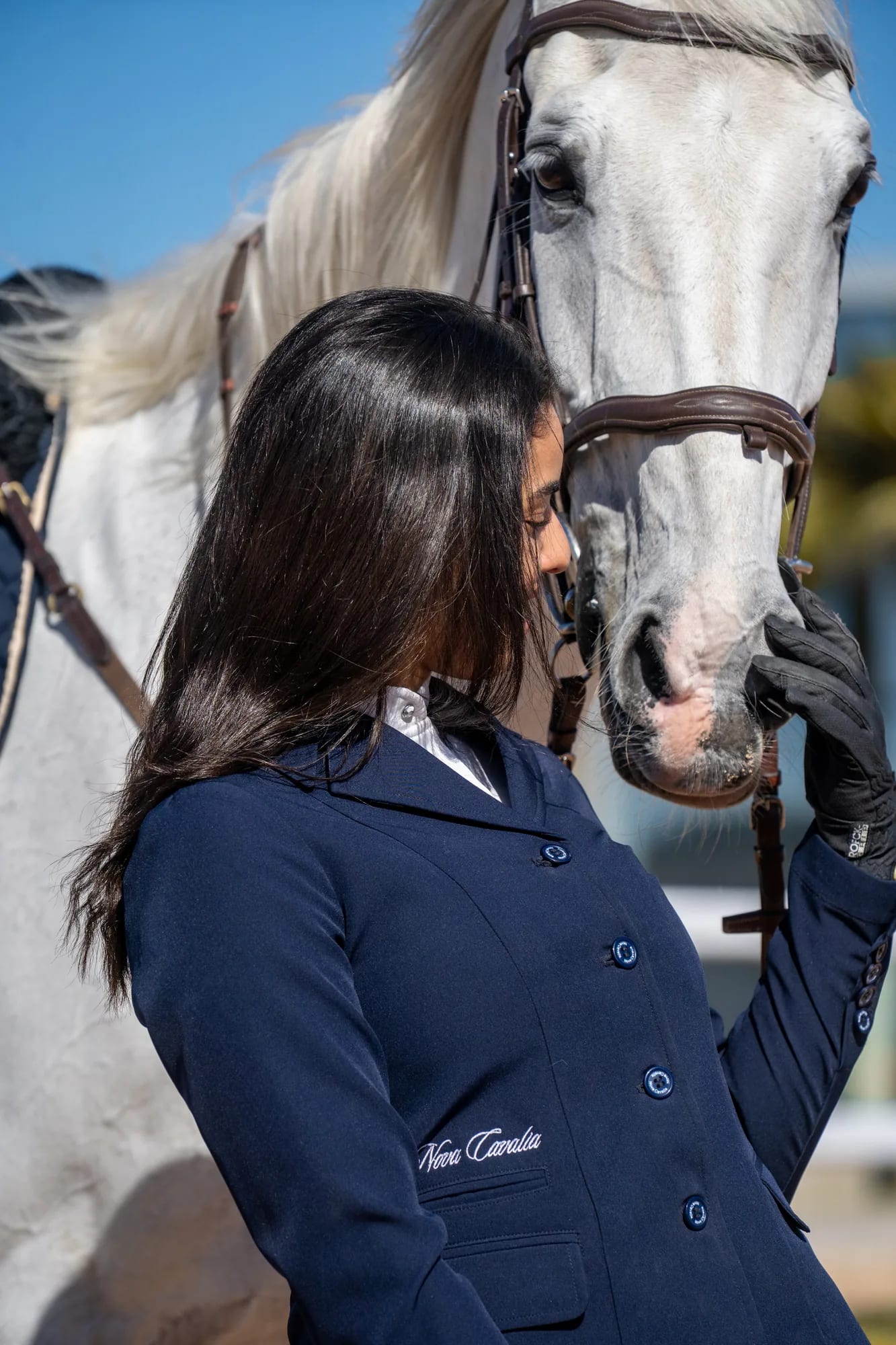 Cavaliere en veste de concours partageant un instant avec son cheval